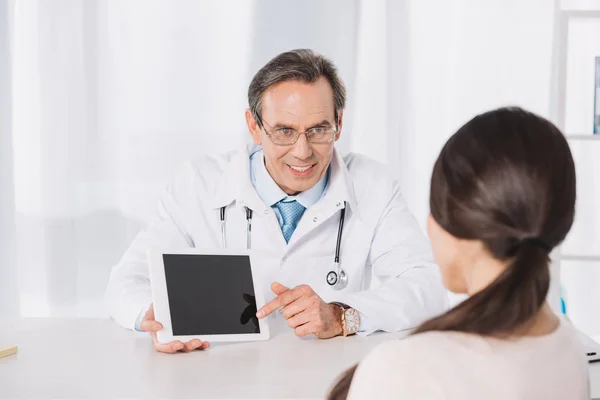 Doctor mostrando algo en el comprimido al paciente femenino - foto de stock