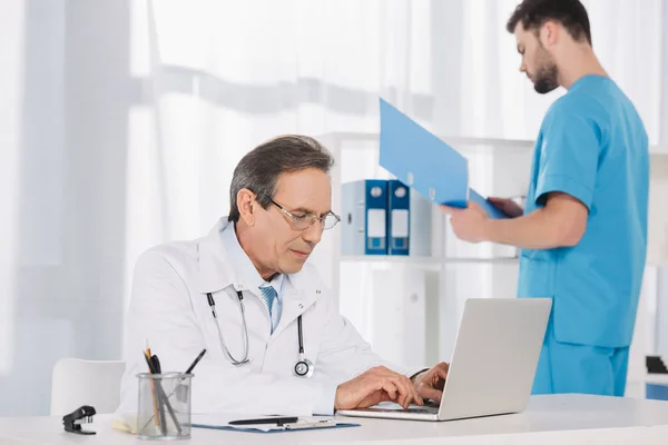 Médico do sexo masculino trabalhando no laptop na clínica — Fotografia de Stock