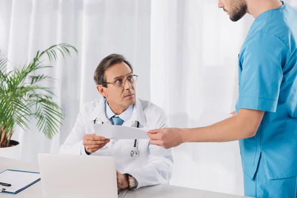 Cropped image of doctor giving documents to nurse — Stock Photo