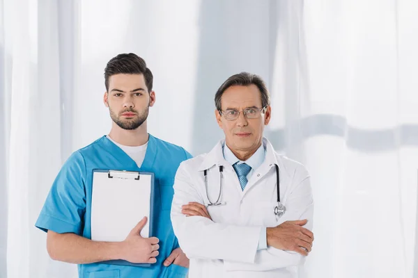 Чоловіча медсестра і лікар стоїть і дивиться на камеру — стокове фото