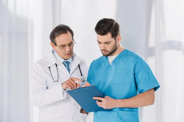 Male doctor and nurse looking at clipboard — Stock Photo