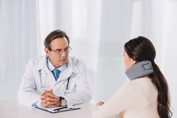 Medico che siede e parla con il paziente con il collare — Foto stock