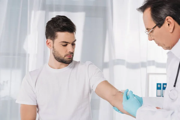 Médico tomando sangue de paciente para teste em luvas médicas — Fotografia de Stock