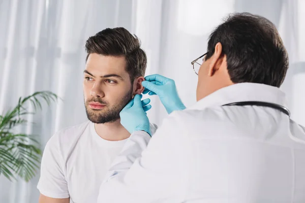 Médico examinando oído paciente masculino - foto de stock