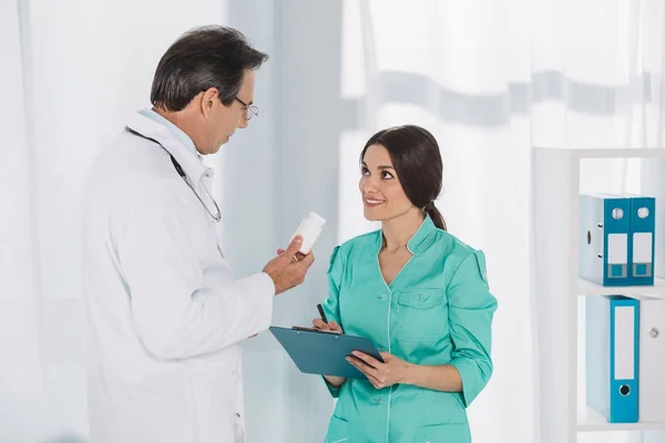 Medico mostrando pillole per infermiera sorridente — Foto stock