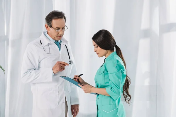 Krankenschwester schreibt nach Arzt in Klemmbrett — Stockfoto