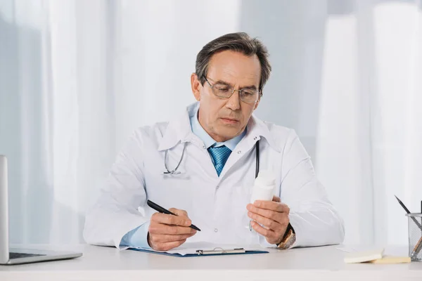 Лікар тримає ручку і дивиться на таблетки — Stock Photo