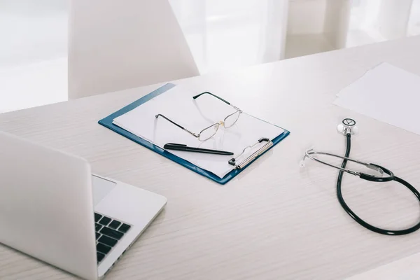 Стаканы и ручка на рабочем столе в больнице — стоковое фото