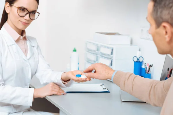 Partial view of doctor showing contact lens to patient in clinic — Stock Photo