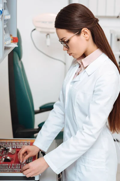 Side view of oculist choosing lens for trial frame in clinic — Stock Photo