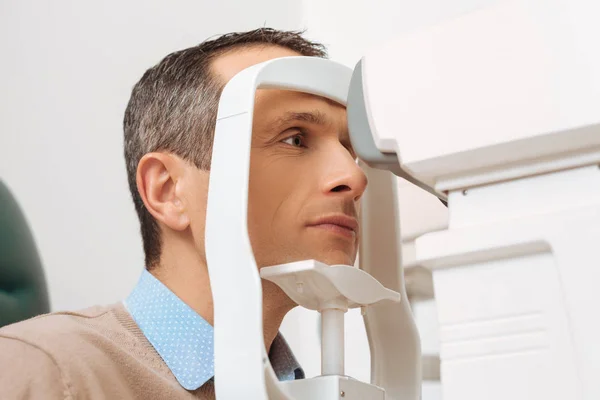 Vue latérale du patient obtenant l'oeil vérifié dans la clinique — Photo de stock