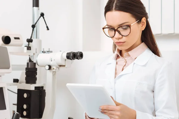 Retrato de optometrista focado usando tablet digital na clínica — Fotografia de Stock