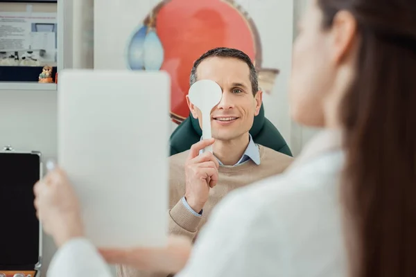 Selektiver Fokus des lächelnden Mannes bei Augenuntersuchung durch Augenarzt in Klinik — Stockfoto