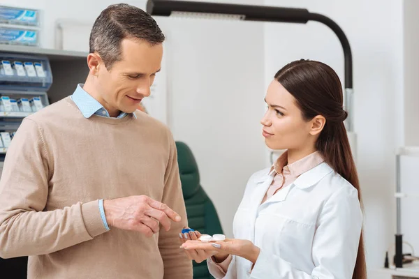 Portrait of ophthalmologist show contact lens to patient in clinic — Stock Photo