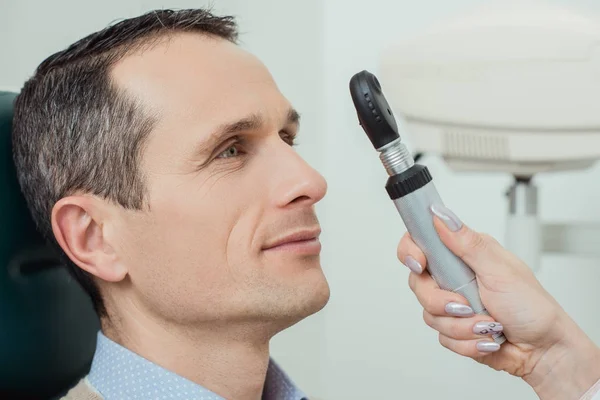 Side view of man getting eye test by ophthalmologist in clinic — Stock Photo