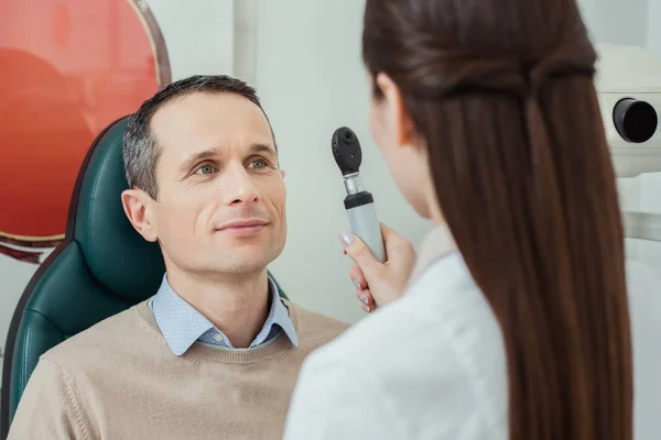Retrato del hombre haciéndose la prueba ocular por el oftalmólogo en la clínica - foto de stock