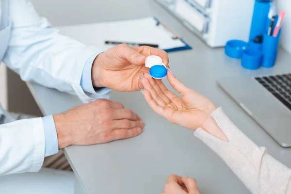 Обрезанный снимок офтальмолога, дающего контактные линзы пациенту в клинике — стоковое фото