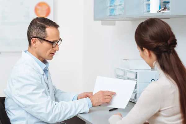 Vue latérale du patient à la réception des médecins à la clinique — Photo de stock