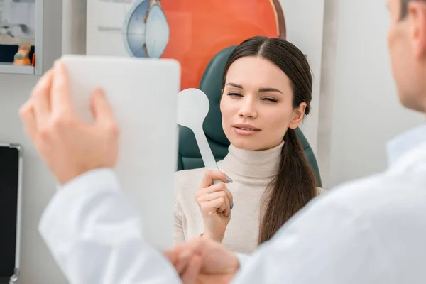 Partial view of young woman getting eye test by oculist in clinic — Stock Photo