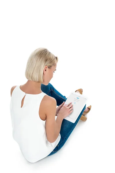 Vista posterior de mujer rubia usando tableta digital con aplicación skype, aislado en blanco - foto de stock