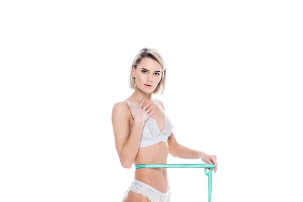 Chocada chica en lencería midiendo su delgada cintura, aislada en blanco — Stock Photo