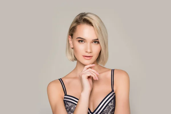 Jolie fille blonde coûteuse posant en soutien-gorge noir, isolé sur gris — Photo de stock