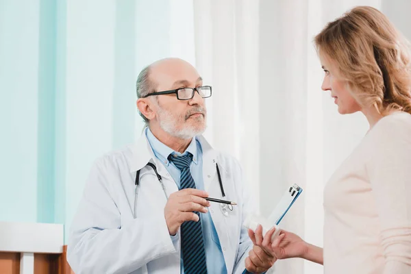 Side view of senior doctor and female patient with medicines in hand in clinic — Stock Photo