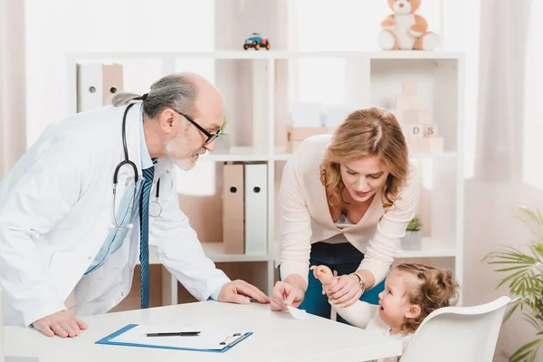 Mother and crying little daughter at doctors reception in clinic — Stock Photo