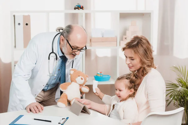 Madre e hija pequeña en la recepción de los médicos en la clínica - foto de stock