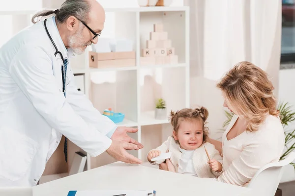 Мати і плаче маленька дочка на прийомі лікарів у клініці — стокове фото