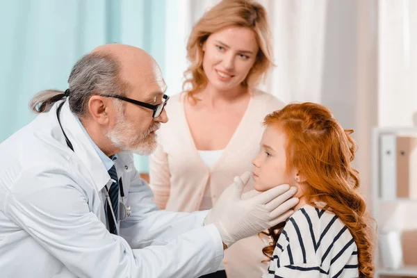 Selective focus of doctor in medical gloves examining little patients throat in clinic — Stock Photo