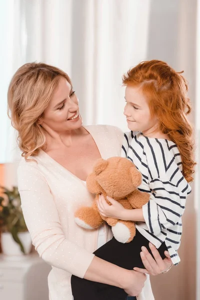 Portrait of smiling mother holding little daughter with teddy bear — Stock Photo