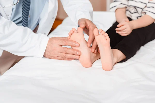Обрезанный снимок доктора, осматривающего детские ступни в больнице — стоковое фото