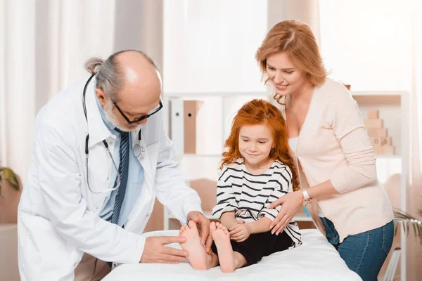 Portrait of doctor examining cute little girl during reception in clinic — Stock Photo