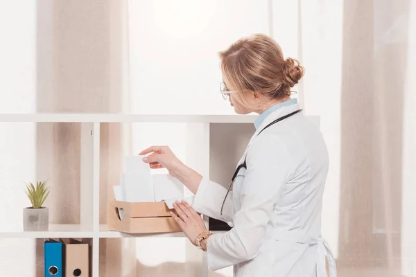 Vista lateral del médico en bata blanca trabajando con espacios en blanco en la clínica - foto de stock
