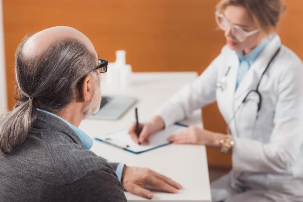 Enfoque selectivo del paciente mayor en la recepción de los médicos en la clínica - foto de stock