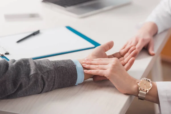 Colpo ritagliato di medico donna che controlla il polso dei pazienti sul posto di lavoro in clinica — Foto stock