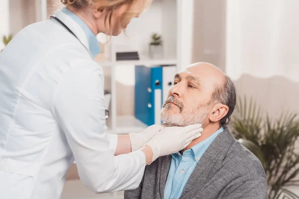 Arzt mit Handschuhen kontrolliert Patienten in Klinik die Kehle — Stockfoto