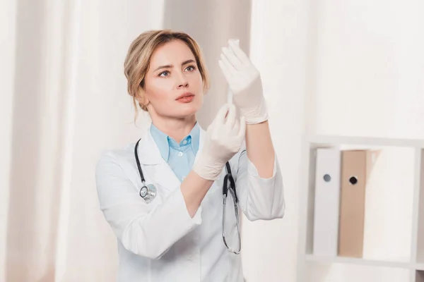 Портрет врача в белом халате и медицинских перчатках, держащего шприц для инъекций в руках в клинике — стоковое фото