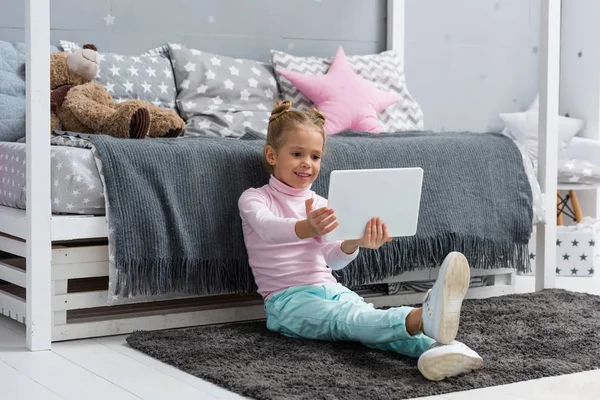 Niño feliz sentado en el suelo y el uso de la tableta - foto de stock