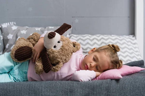 Adorable little kid sleeping on couch with teddy bear — Stock Photo