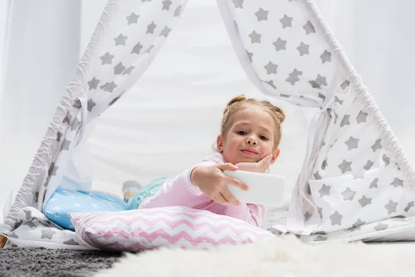 Adorabile bambino prendendo selfie in teepee artigianale a casa — Foto stock