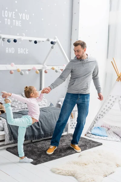 Красивый молодой отец танцует с дочерью в детской спальне — стоковое фото