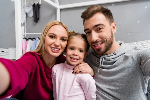 Feliz jovem família tomando selfie no quarto de criança — Fotografia de Stock