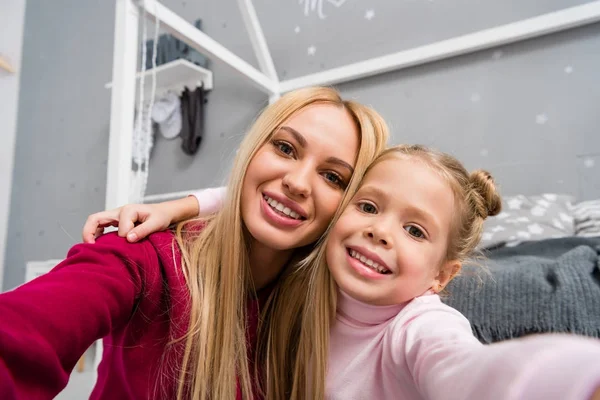 Close-up shot of young smiling mother and daughter looking at camera — Stock Photo