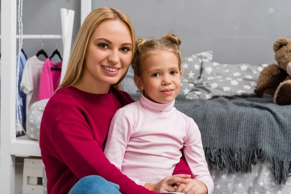 Junge schöne Mutter und entzückende Tochter umarmen sich im Schlafzimmer — Stockfoto