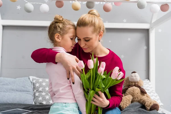 Daughter presenting tulips bouquet for happy young mother on mothers day — Stock Photo