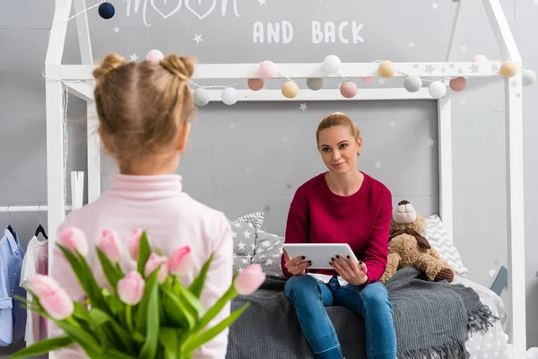 Tochter versteckt Tulpenstrauß für Mutter hinter Rücken — Stockfoto