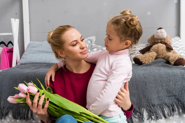 Adorável filhinha apresentando buquê de tulipas para a mãe no dia das mães — Fotografia de Stock