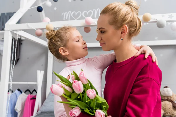 La piccola figlia che presenta il mazzo di tulipani a madre durante giorno di madri — Foto stock